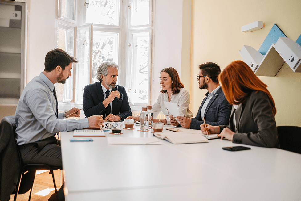 Business meeting with five people discussing strategy.